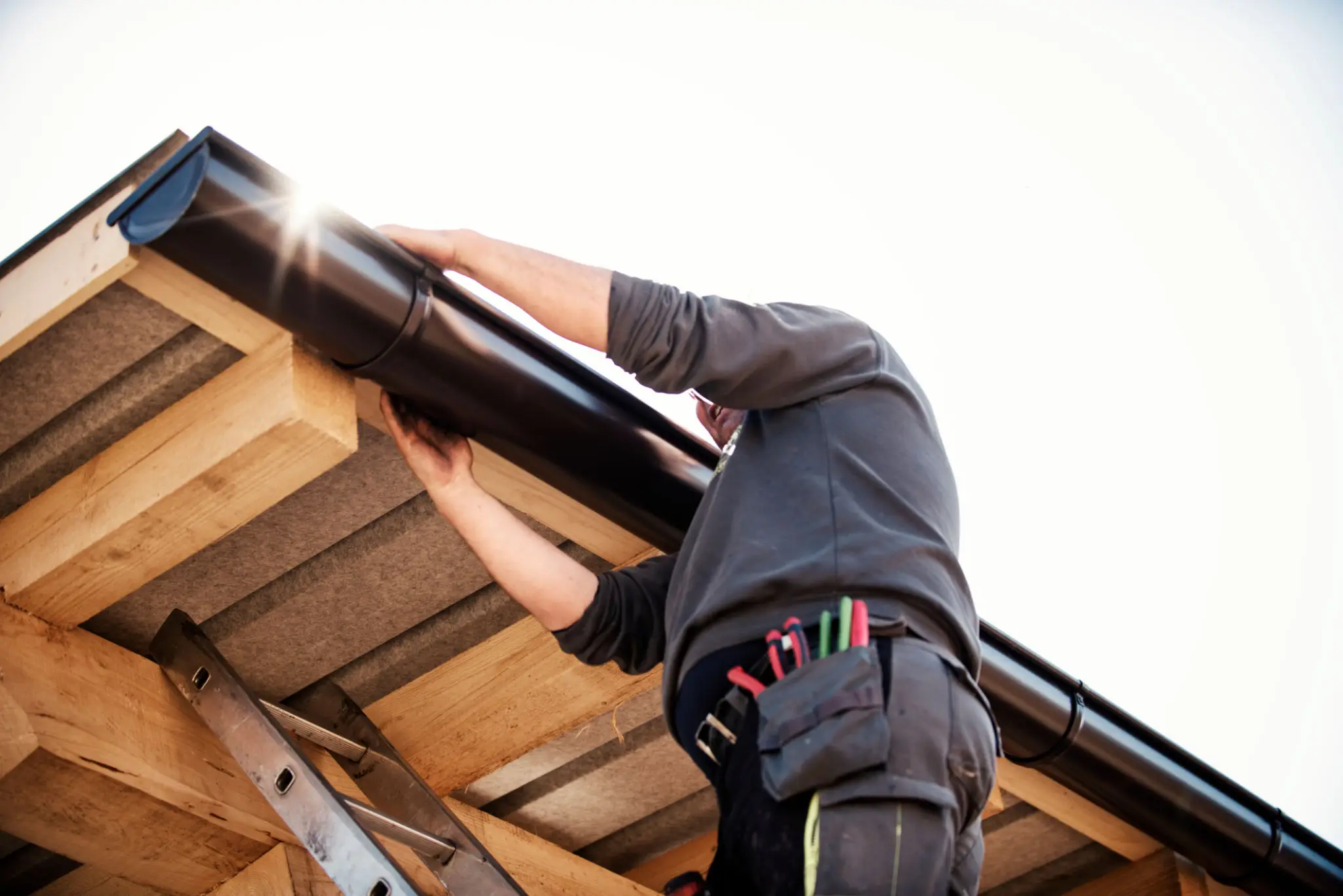 Person installing or repairing a gutter on a roof.